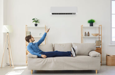 Man With Remote Control From Air Conditioner Makes Comfortable Temperature For Himself.